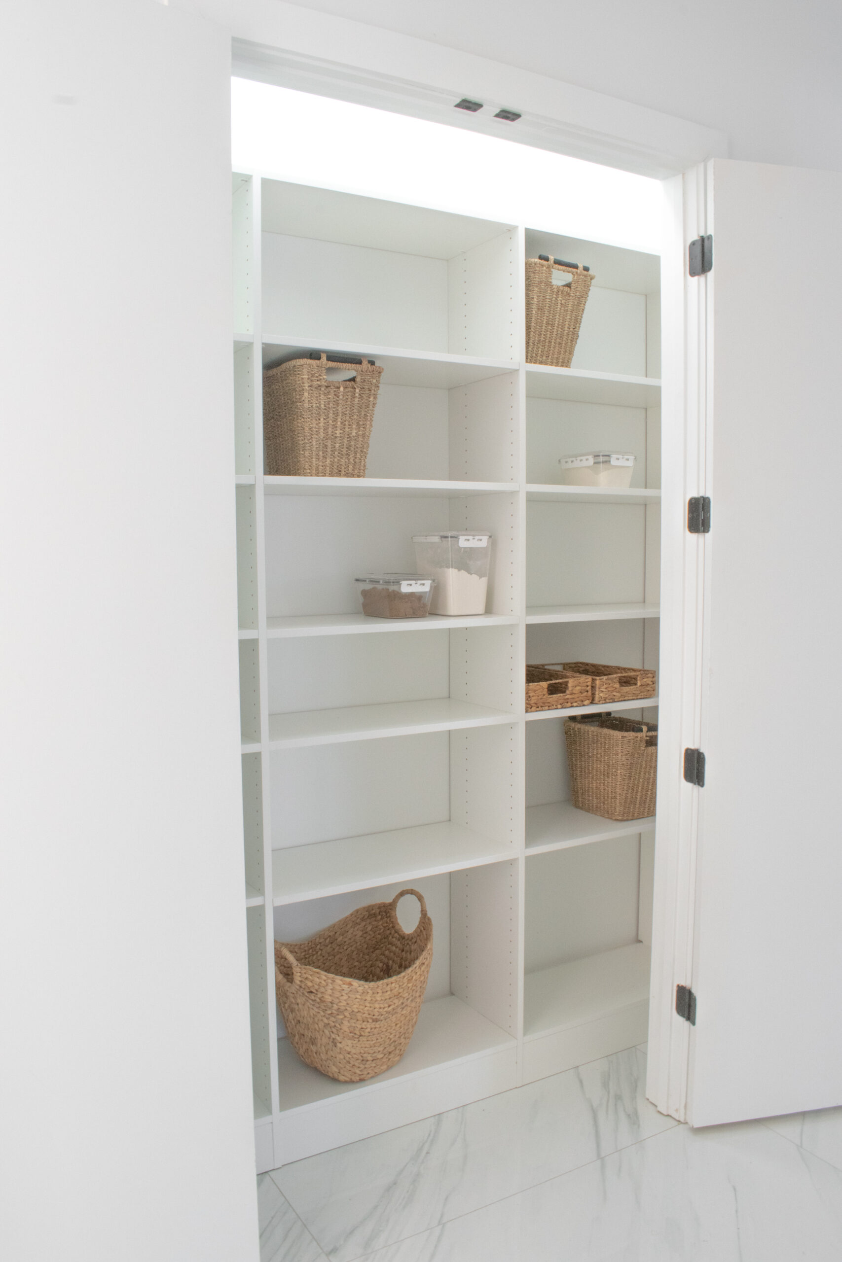 Small white reach-in pantry with adjustable shelves and a built-in base by Custom Closets of GA.